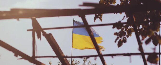Ukraine flag flying behind the shell of a building