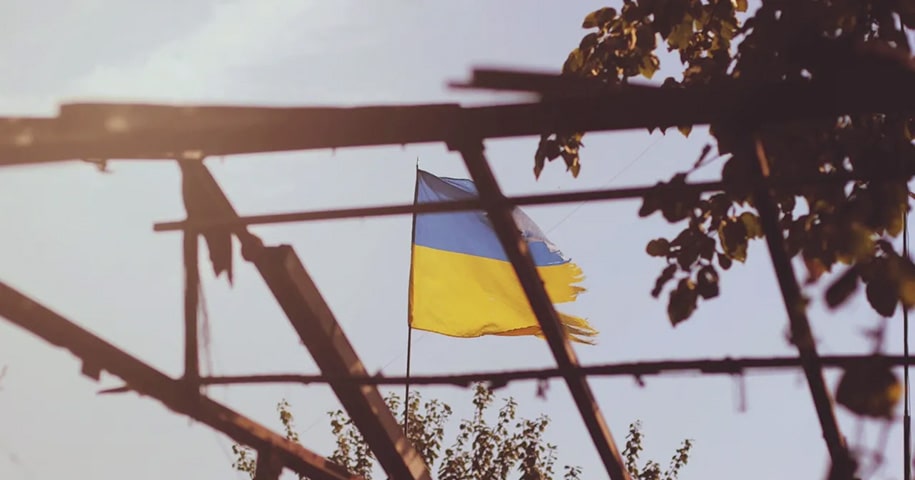 Ukraine flag flying behind the shell of a building