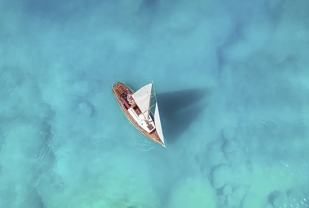 Birds eye view of a yacht sailing in clear waters