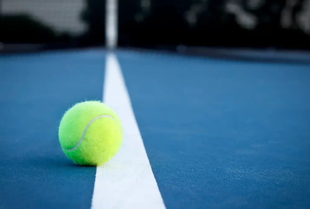 Tennis ball sitting on the court line