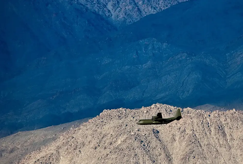 Military plane flying over mountains